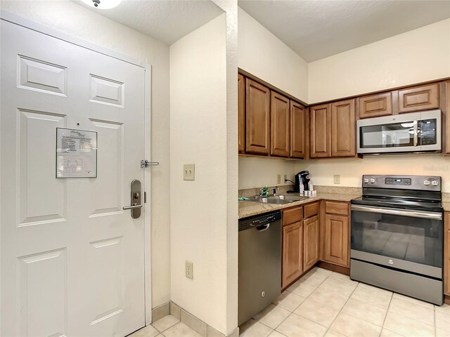 kitchen with appliances with stainless steel finishes, light tile patterned flooring, and sink