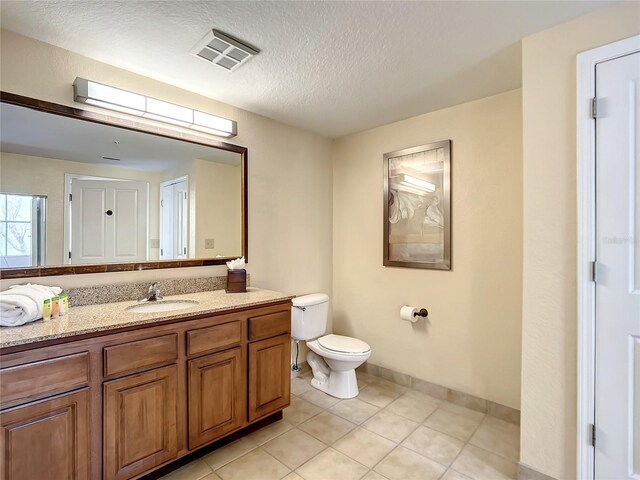 bathroom with tile patterned floors, vanity, a textured ceiling, and toilet