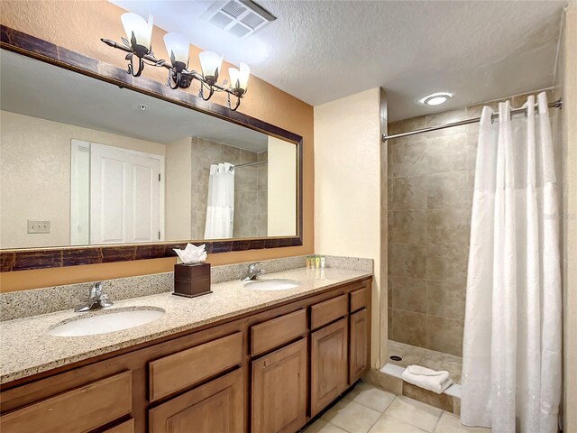 bathroom featuring a textured ceiling, curtained shower, dual bowl vanity, and tile patterned floors