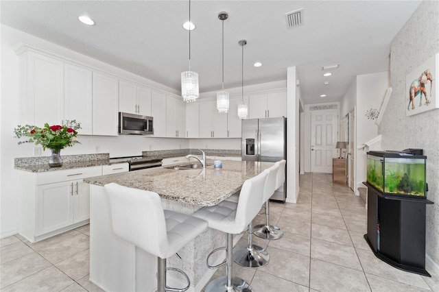 kitchen with an island with sink, sink, stainless steel appliances, and white cabinetry