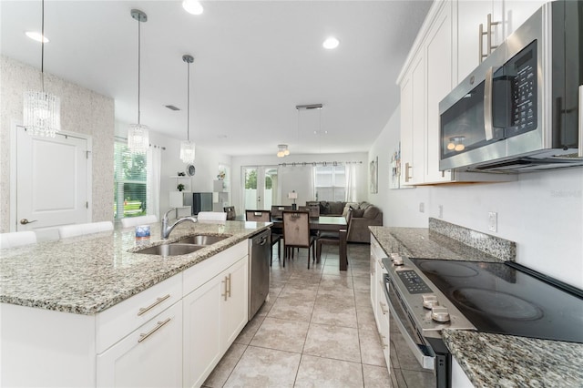 kitchen featuring appliances with stainless steel finishes, an island with sink, light stone countertops, white cabinets, and sink