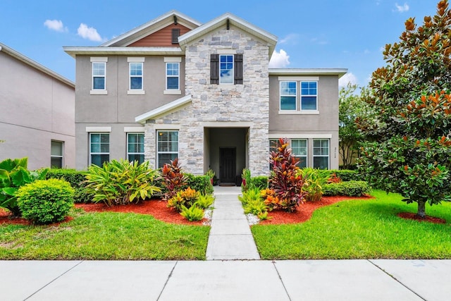 view of front of property featuring a front yard, stone siding, and stucco siding