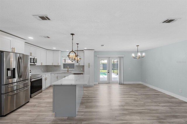 kitchen with decorative backsplash, appliances with stainless steel finishes, light hardwood / wood-style flooring, sink, and a kitchen island