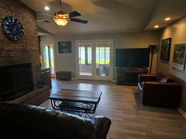 living room with ceiling fan, a fireplace, lofted ceiling, and hardwood / wood-style flooring