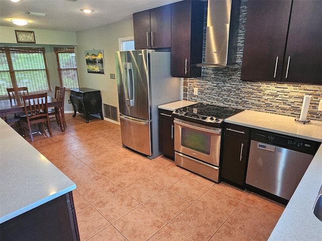 kitchen featuring decorative backsplash, light tile patterned floors, stainless steel appliances, and wall chimney range hood