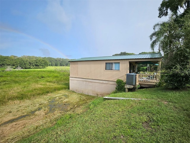 view of side of home with central AC unit and a lawn