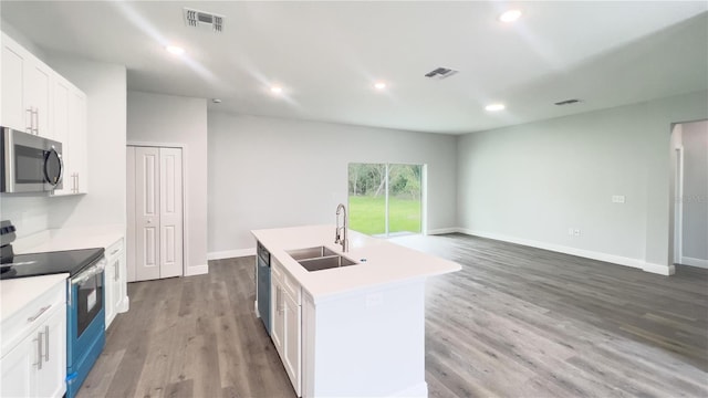 kitchen with white cabinets, appliances with stainless steel finishes, sink, wood-type flooring, and an island with sink