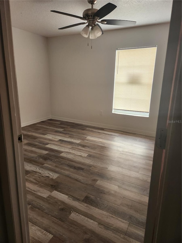 spare room with dark wood-type flooring, ceiling fan, and a textured ceiling