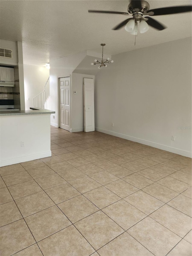 unfurnished living room featuring a textured ceiling, light tile patterned flooring, and ceiling fan with notable chandelier