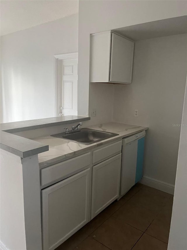 kitchen with dark tile patterned flooring, light stone countertops, sink, and dishwasher