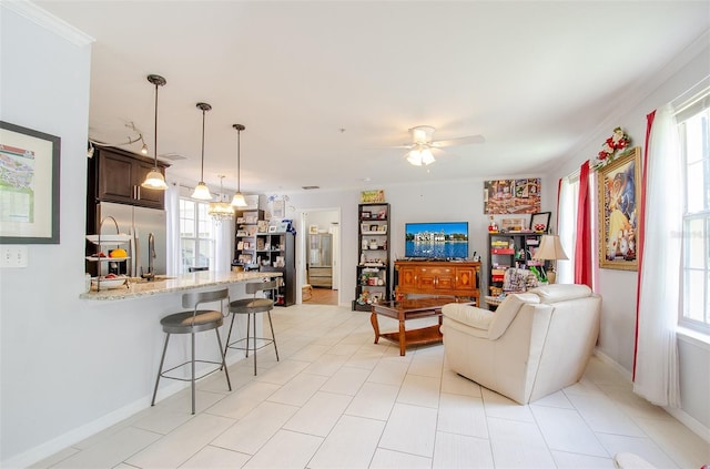 living room featuring plenty of natural light, a ceiling fan, and baseboards