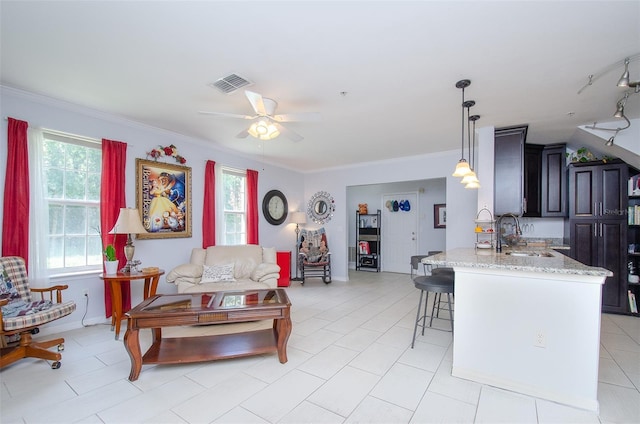 living area featuring a ceiling fan, baseboards, visible vents, and crown molding