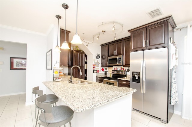 kitchen with stainless steel appliances, a sink, visible vents, dark brown cabinets, and a kitchen bar