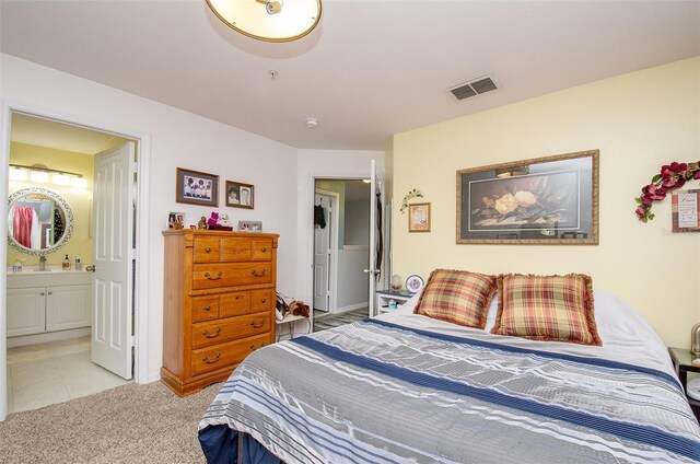 bedroom with visible vents, a sink, light carpet, and ensuite bath