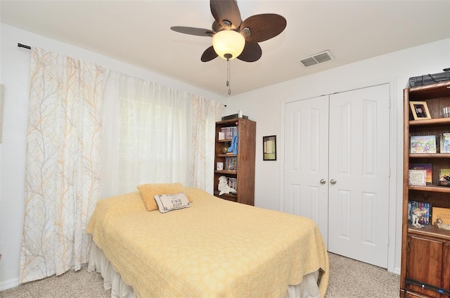 bedroom with a ceiling fan, visible vents, a closet, and light colored carpet