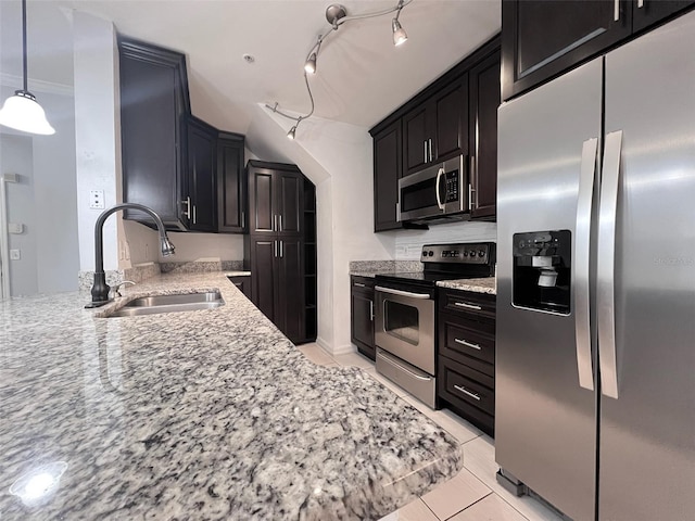 kitchen with light stone counters, dark cabinets, stainless steel appliances, a sink, and ornamental molding