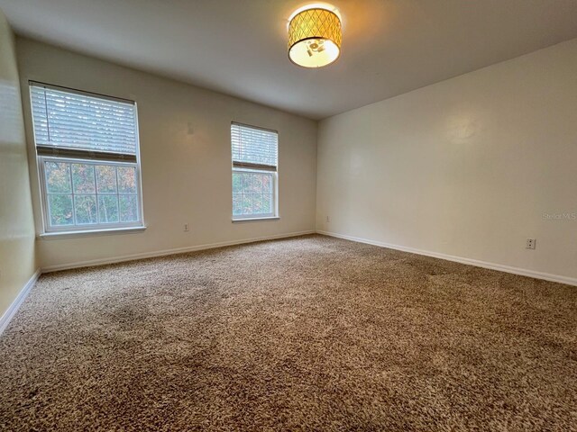 unfurnished room featuring carpet floors and baseboards