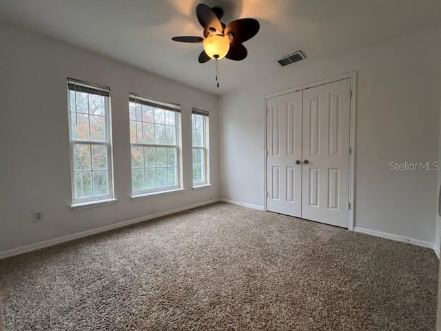 unfurnished bedroom with multiple windows, carpet flooring, visible vents, and baseboards