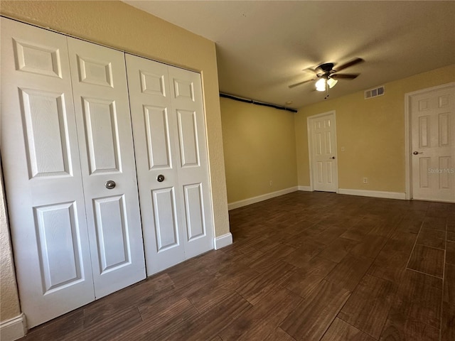 unfurnished bedroom with ceiling fan, a closet, and dark wood-type flooring