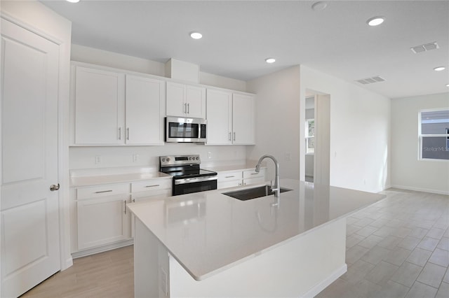 kitchen with sink, white cabinetry, stainless steel appliances, and a kitchen island with sink