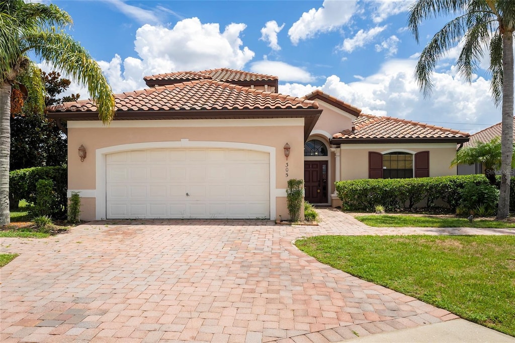 mediterranean / spanish-style home with a front lawn and a garage