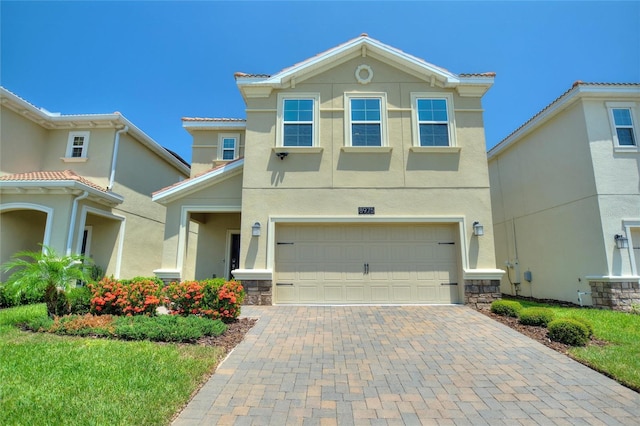 view of front of home with decorative driveway, stone siding, stucco siding, and a garage