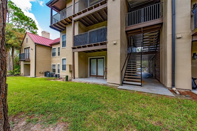 exterior space featuring a lawn, a balcony, a patio, and central AC