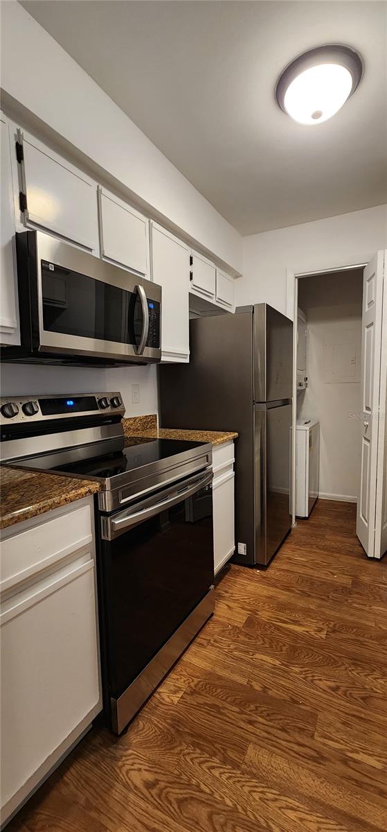 kitchen featuring white cabinetry, stainless steel appliances, washer and clothes dryer, and dark wood-type flooring