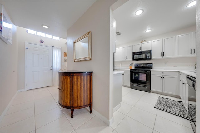 kitchen with light tile patterned floors, sink, black appliances, and white cabinetry