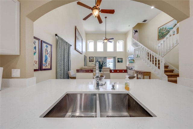 kitchen with ceiling fan, a towering ceiling, white cabinetry, and pendant lighting