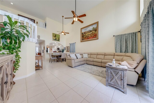 living room with a towering ceiling, light tile patterned flooring, and ceiling fan