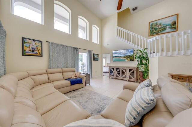 living room with light tile patterned flooring, ceiling fan, and a high ceiling