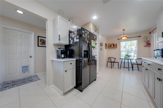 kitchen featuring black fridge with ice dispenser, decorative light fixtures, white cabinetry, and light tile patterned floors