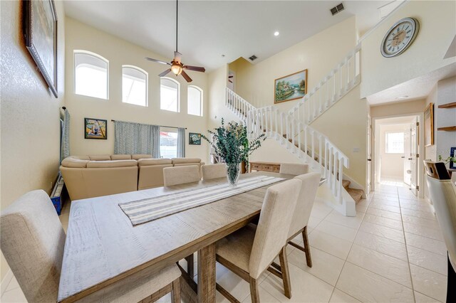 tiled dining area with ceiling fan and a high ceiling