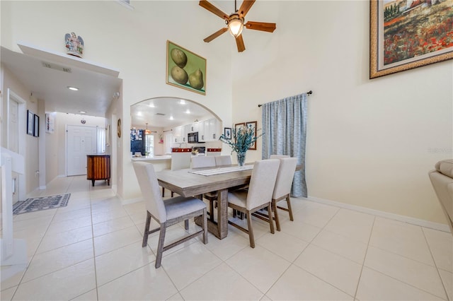 dining space featuring a towering ceiling, light tile patterned flooring, and ceiling fan