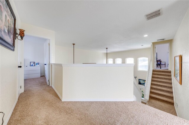 hall with a notable chandelier and light colored carpet