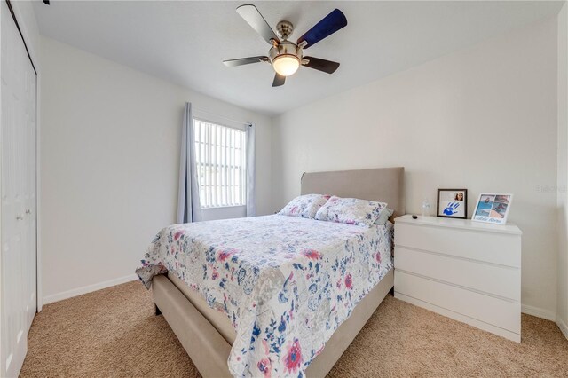 bedroom with ceiling fan, a closet, and light colored carpet