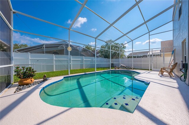 view of swimming pool with glass enclosure and a patio