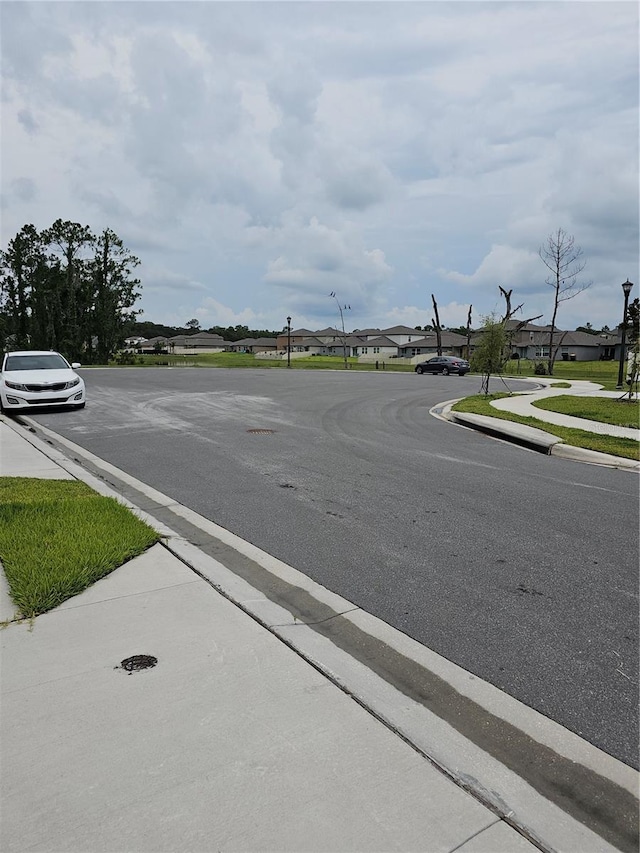 view of street featuring sidewalks, a residential view, curbs, and street lights