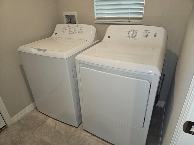 clothes washing area featuring washing machine and clothes dryer, laundry area, and baseboards