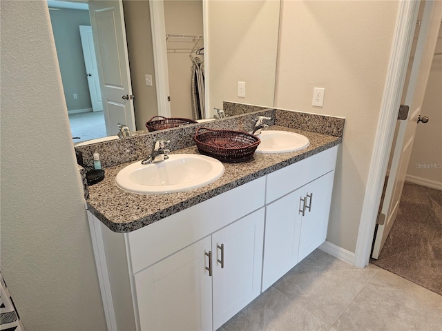 full bathroom with a sink, baseboards, double vanity, and tile patterned floors