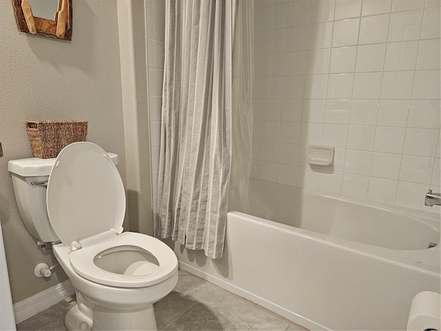 full bathroom with baseboards, shower / bath combo, tile patterned floors, toilet, and a textured wall