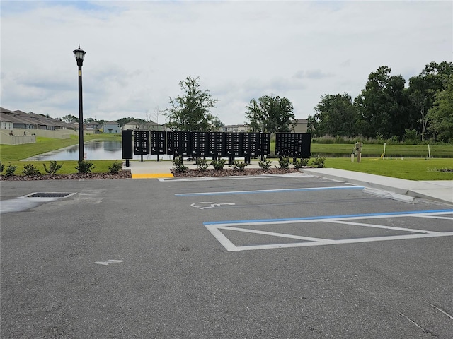 uncovered parking lot featuring mail area and a water view