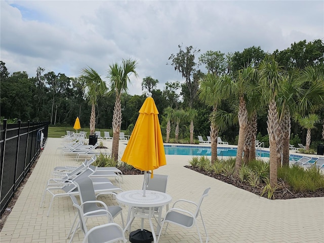 view of patio / terrace with a community pool and fence