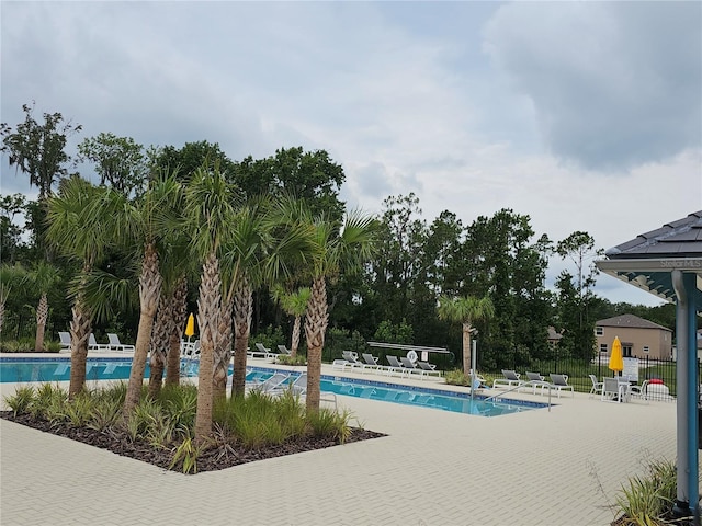 community pool with a patio area and fence