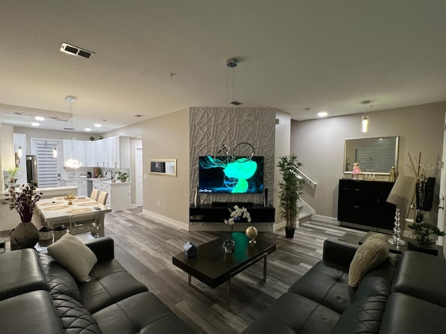 living area with baseboards, visible vents, wood finished floors, and recessed lighting