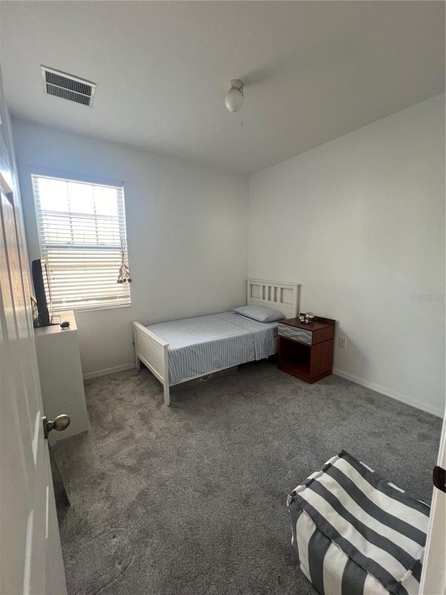 bedroom with dark carpet, visible vents, and baseboards