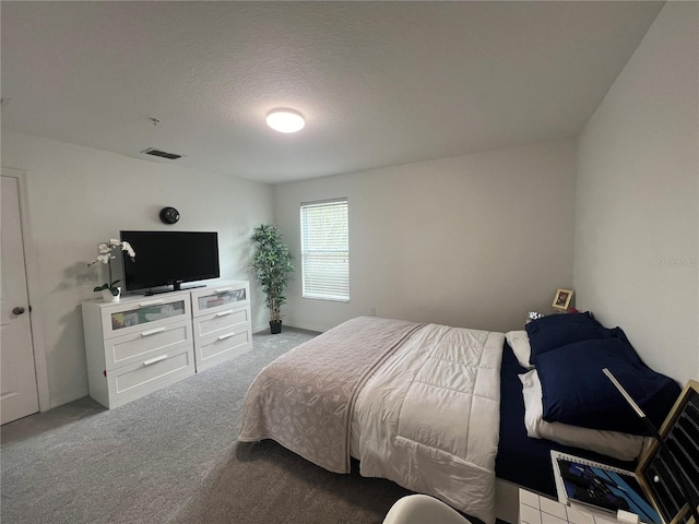 bedroom featuring visible vents, a textured ceiling, and light colored carpet