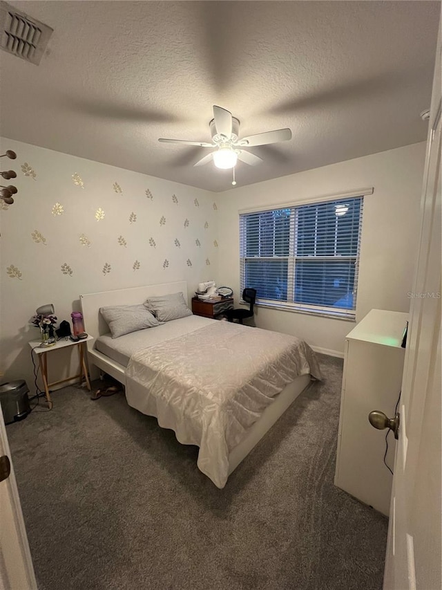 bedroom with a textured ceiling, ceiling fan, visible vents, dark colored carpet, and wallpapered walls