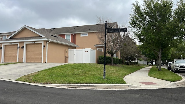 view of property featuring driveway, a garage, stucco siding, a gate, and a front yard